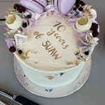 a tall cake covered in purple macrons and icing, reading in gold lettering 10 years of SUAW